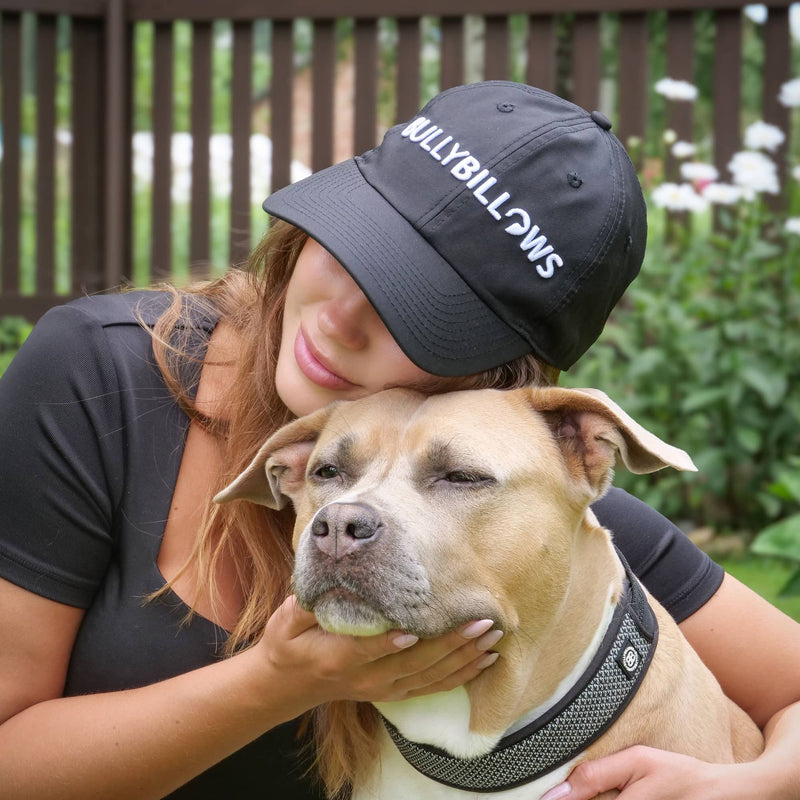 Person wearing a 'BULLYBILLYBOYS' cap kissing a dog outdoors.