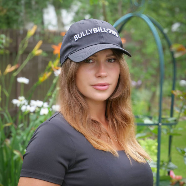 Woman wearing a cap with 'BULLYBILLIOWS' text in a garden setting